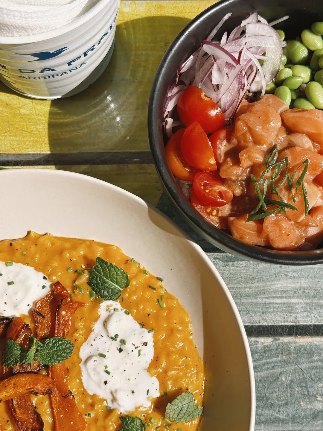 Poke bowl de salmão com tomate-cereja, cebola roxa e edamame, ao lado de um risotto de abóbora com creme e hortelã